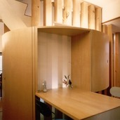 円形の印象的な収納棚と共に造り付けのダイニングテーブル