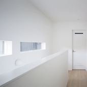 白い空間に日差しを取り込む階段横の窓