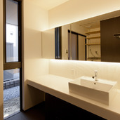 間接照明の柔らかい光と焦げ茶色のタイルが、落ち着いた雰囲気のある洗面空間に