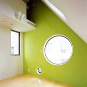 丸い窓とグリーンの壁が印象的な部屋