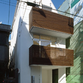 白い外壁と、木目が美しいルーバーが特徴の都市型住宅の外観