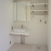 バスルームと同じ白い床タイルを使用した、コンパクトにまとめた洗面所