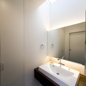 天井からの光、アッパー＆ダウン照明がふんわりとした空気を生むシンプルな洗面所