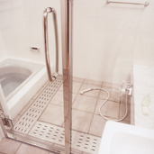 水気を切りやすいように排水部分を多めにした、ガラス扉でスッキリとまとめた在来浴室