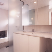 床壁を小さなグレー色のタイルでまとめた、すっきりとした洗面所・浴室