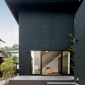 黒い面積が多い外壁から伸びるように広がる中庭