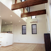 太い梁をデザインとして処理した、吹き抜けのあるリビング空間