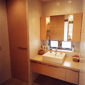 床壁にタイルを使用した、ぬくもりを感じる木を多く使った洗面所