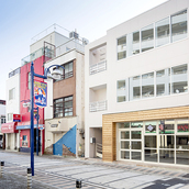 モダンな街並に淡い色の外壁が映える外観