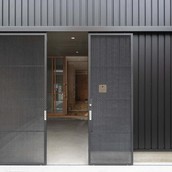 細身のエキスパンドメタル親子吊戸。普段は大きい戸を固定し小さい戸のみ開閉。自転車やバイクの出し入れ時は大小の戸を控壁へ収めて全開放。