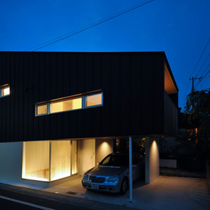 家の灯りと黒壁のコントラストが美しい夜の外観