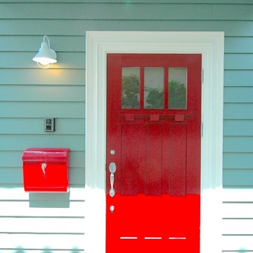 ミントグリーンの外壁にビビットな赤いドアが映えるカラフルな玄関