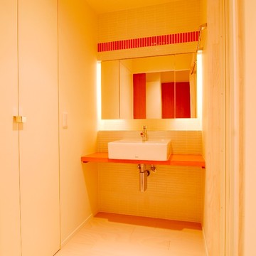 鏡裏の照明と赤いタイルがおしゃれな洗面スペース