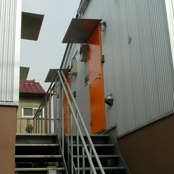 ガルバリウムの外壁に鮮やかなオレンジ色の玄関ドア