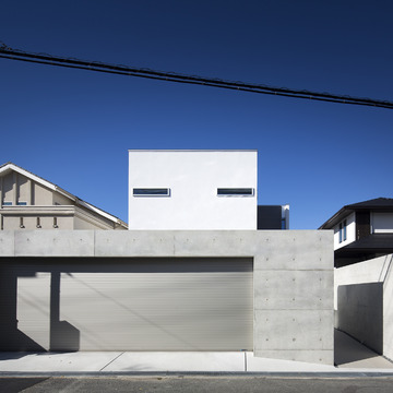 コンクリート打ちっ放し塀とワイドなシャッターが印象的な外観