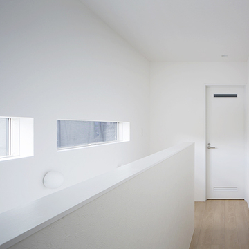 白い空間に日差しを取り込む階段横の窓