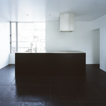 大きめの黒タイル、天井から突き出たような換気扇が、洗練された美を感じるキッチン