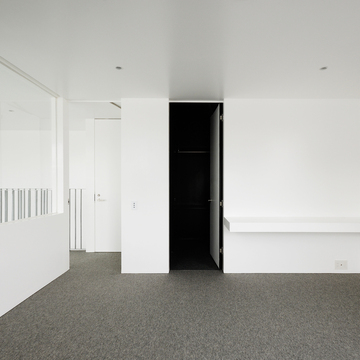 白とグレーで囲まれた部屋内に設けた、引き締まった黒色を用いたウォーキングクローゼット