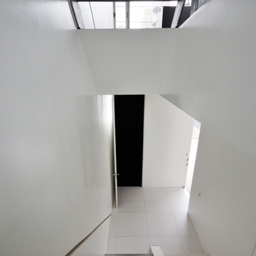 美しい白の床壁と、素材そのものが活かされた階段が新鮮な玄関ホール