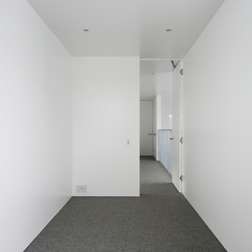 白でまとめた壁・天井がグレーのカーペットを引き立てる洋室