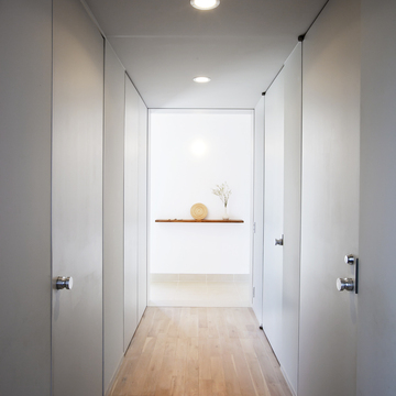 淡いグレーで統一された、全体的に光を絞ったトンネルのような廊下