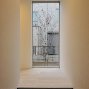 正面に床から天井までのＦＩＸを設け、そこから見えるシンボルツリーが室内にあたたかみを与えている玄関ホール