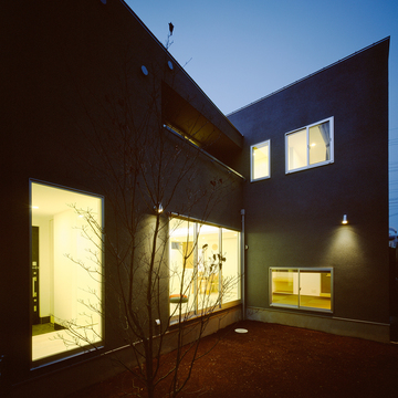 グレーの外壁が闇を作り、窓からこぼれ出る光が美しい中庭