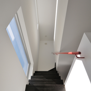 赤い手摺が、各階の家族の空間をつなげていく階段