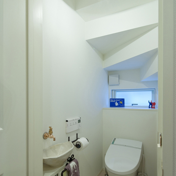 玄関から続く同じタイルで一体感を出した、階段下を立体的に使用したトイレ