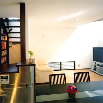 ダイニングキッチンからリビングと開放的な階段を見る