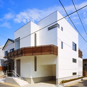 茶色のバルコニーがアクセントの白い外観