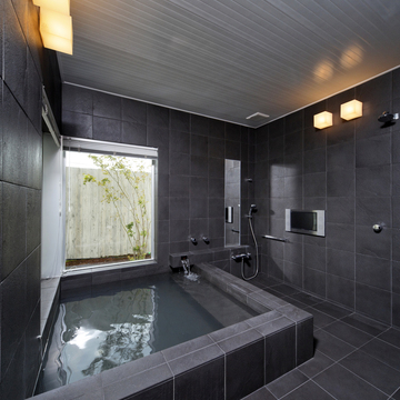 黒のタイル張りが重厚感のある、温泉が引かれた浴室