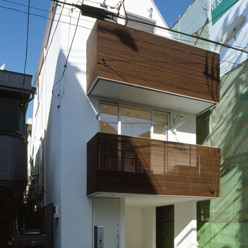 白い外壁と、木目が美しいルーバーが特徴の都市型住宅の外観
