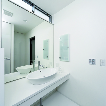 トップライトからの光と壁一面の鏡が、洗面所を広く見せる手段の一つ