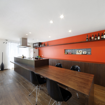 食欲を増す朱色の壁面が、焦げ茶色でまとめた空間にインパクトを与えるキッチン
