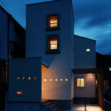 ニッチを兼ねた小さな小窓と、植物の動きを感じるアイアンの面格子が目を引く夜の外観