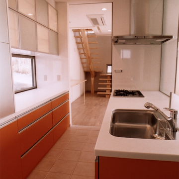 差し色のオレンジ色と、床タイルがよく似合う収納力のあるキッチン