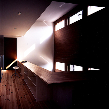 トップライトからの芸術的な光と安らかな影の世界が広がる、手すり部分を収納にした2階吹き抜け部分