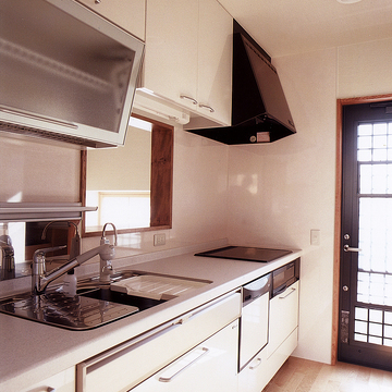 ガラス面を多く使った勝手口ドアから、明るい光が清潔なキッチンに入り込む