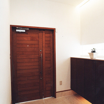 真っ白な壁に、焦げ茶色の木調で仕上げた玄関ドアがポイントのシンプルな玄関