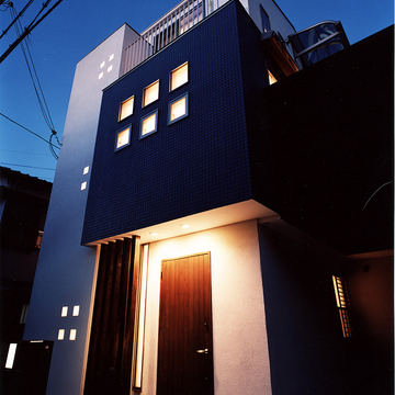 正方形の小さな窓から、建物自体が照明になったかのようにほっこり光を帯びる外観