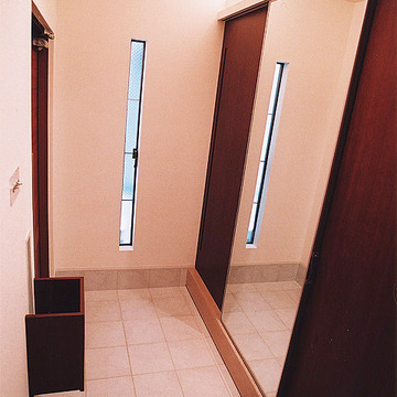 収納用引き戸一枚を可動式鏡に仕立てた、実用性とデザイン性が行き届いた玄関