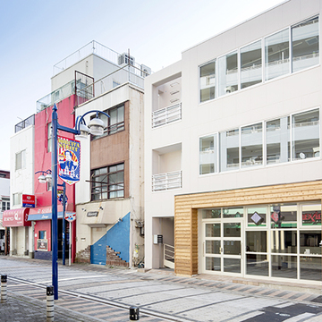 モダンな街並に淡い色の外壁が映える外観