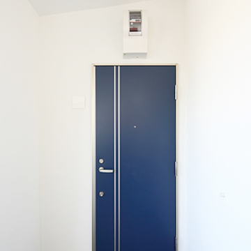 白い壁に映えるネイビーの玄関ドア