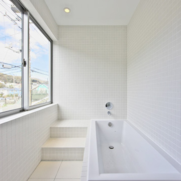 大きな窓のあるタイル張りの明るいバスルーム