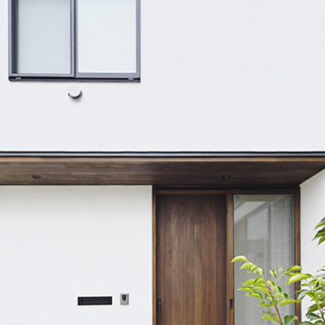 白い壁とコントラストを奏でるウッド調の玄関ドア