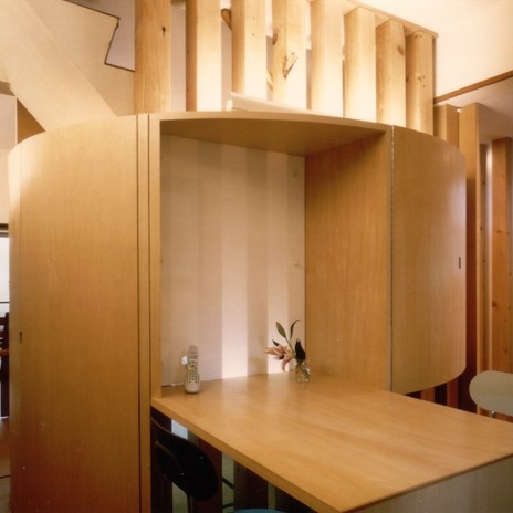 円形の印象的な収納棚と共に造り付けのダイニングテーブル