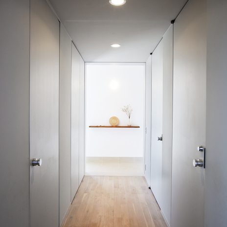 淡いグレーで統一された、全体的に光を絞ったトンネルのような廊下