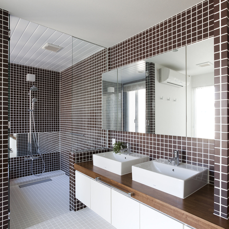 浴室との仕切りガラスが空間に狭さを感じさせない、茶色のタイルが印象的な洗面所