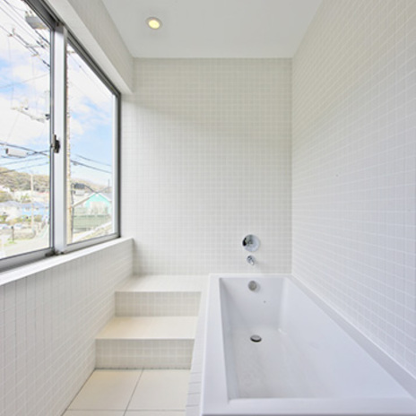 大きな窓のあるタイル張りの明るいバスルーム